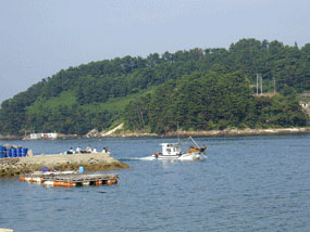 낚시꾼들 앞을 지나가는 통통배 사진